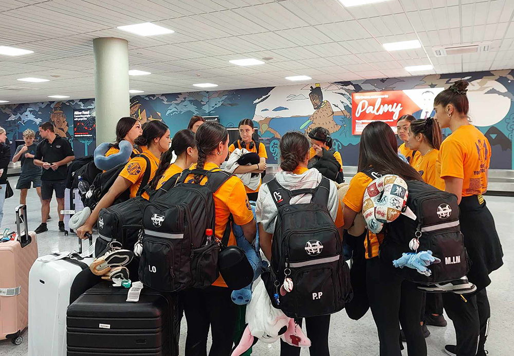 The team standing with their luggage at an airport