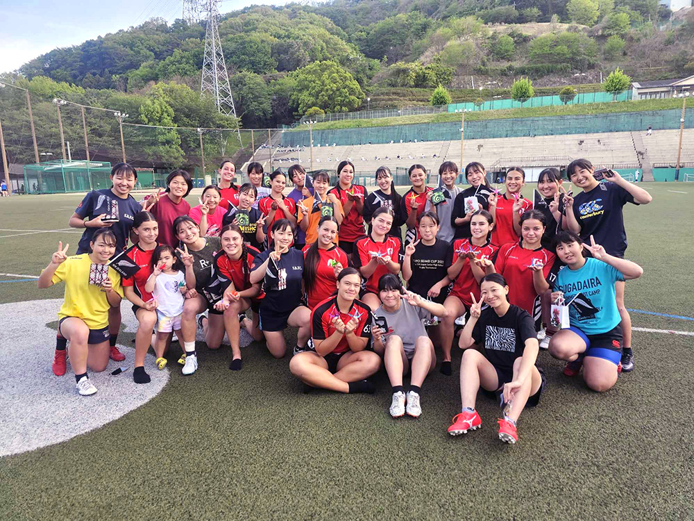The Manukura team posing for a photo on a field with a Japanese team