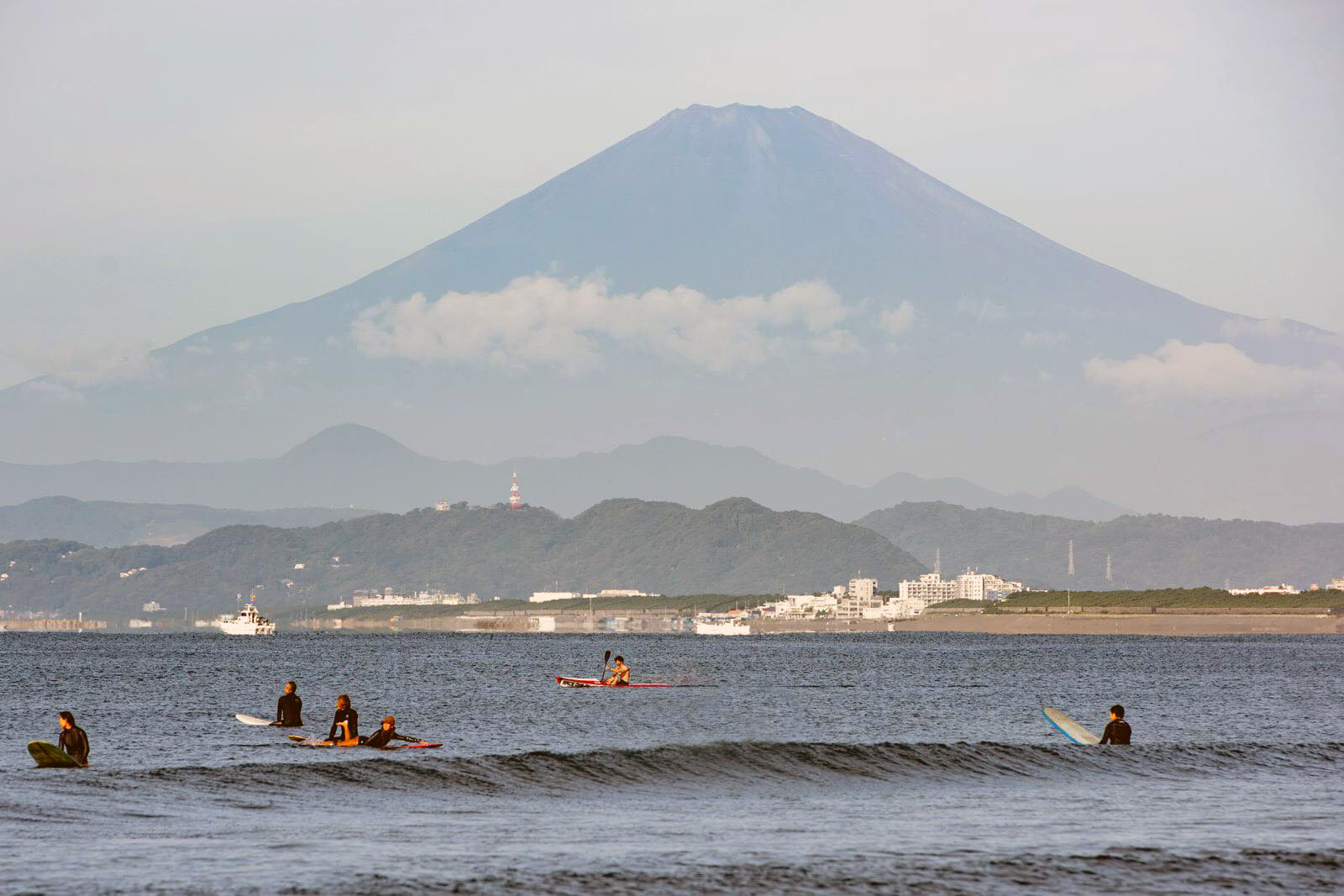 Surfers in the swell with Mount Fuji in the distance
