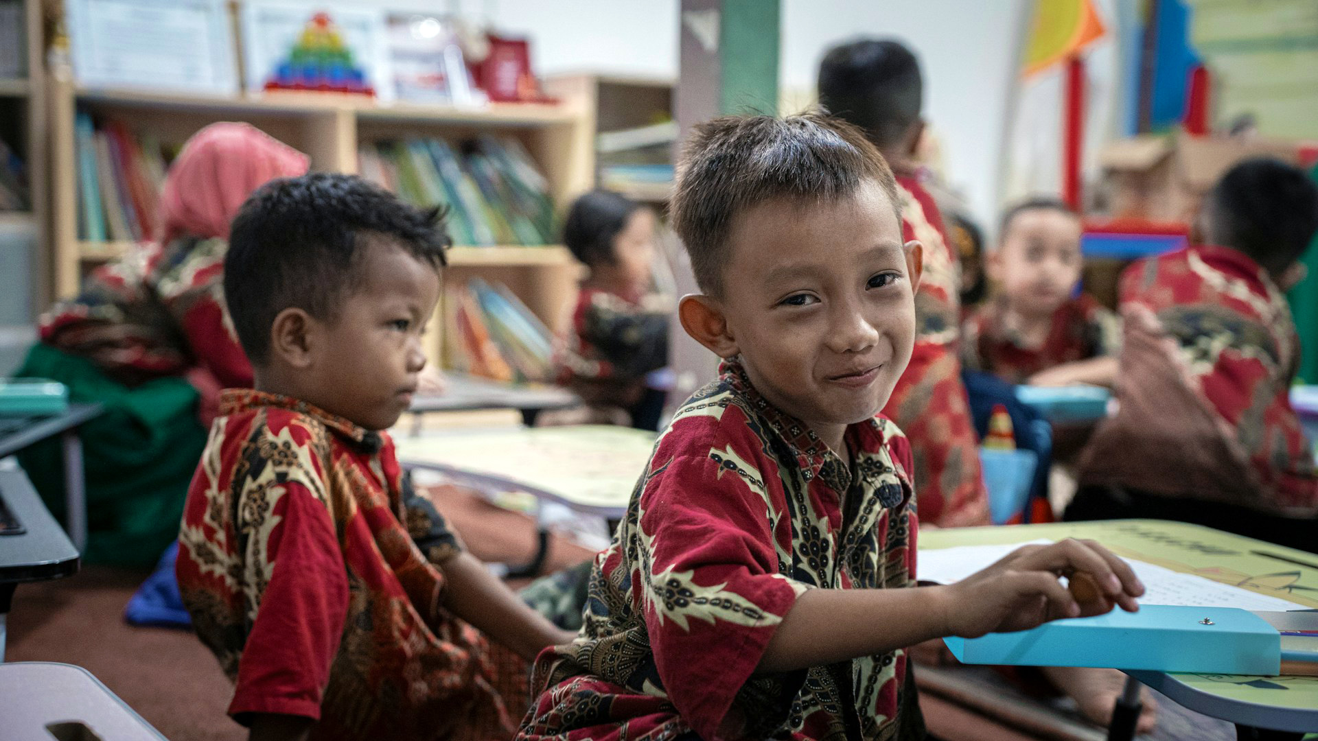 An Indonesian boy smiling at the camera in a classroom