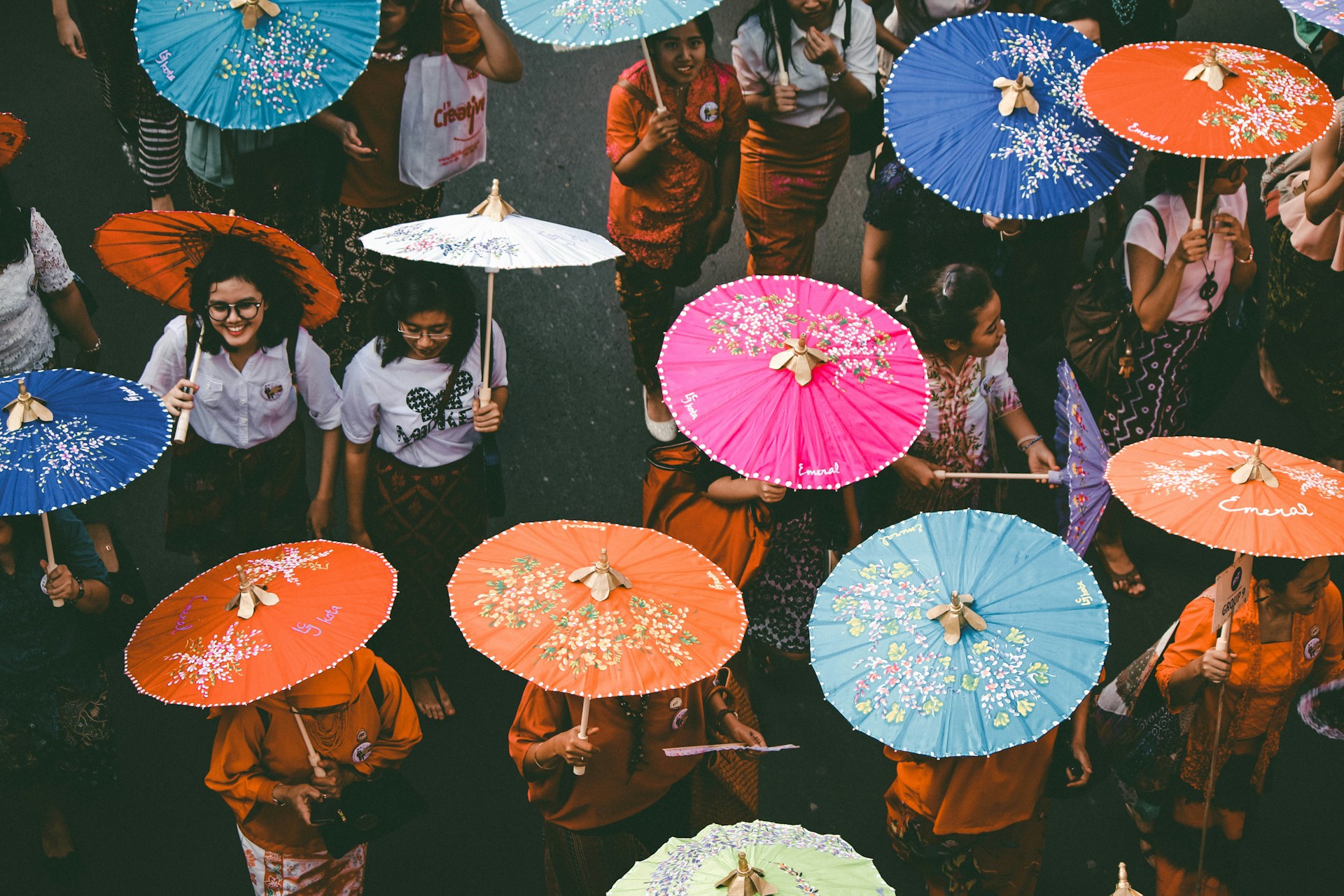 Young women walking on a street carrying sun umbrellas