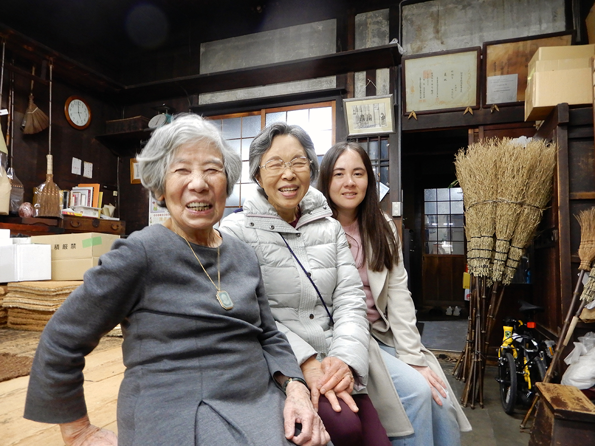 Two older womemn and a young woman sitting on a bench in an old shop