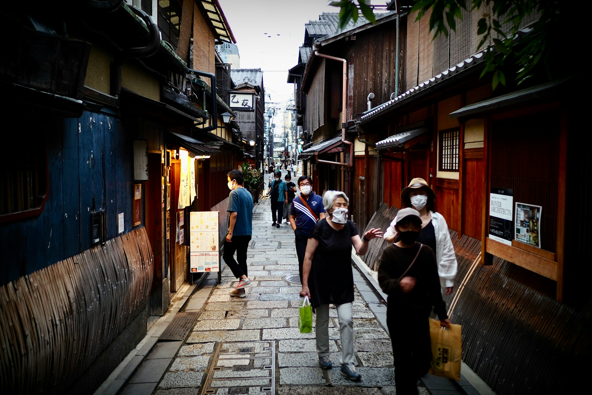 People walking along a Kyoto alley lined with old shops