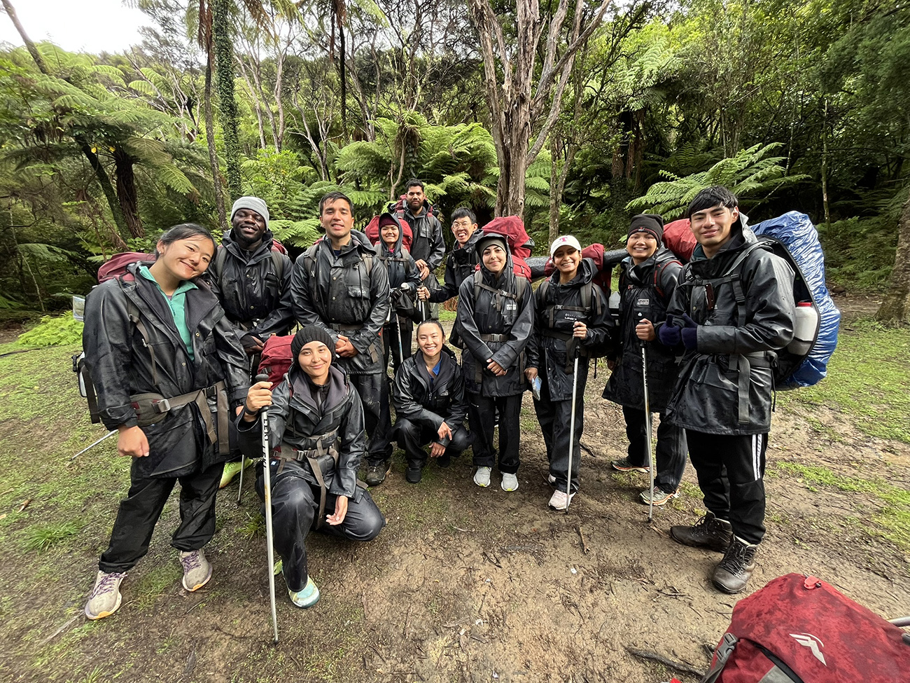Outwardbound trampers posing for a group photo in the bush dressed in wet-weather gear