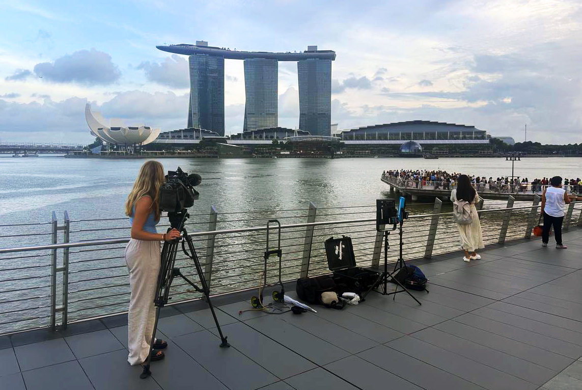A camera woman filming with the famous Marina Bays Sands resort in the background