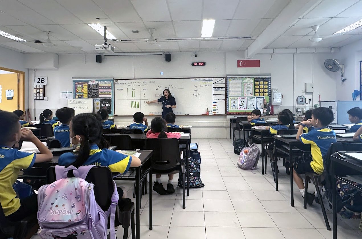 A teacher giving instruction to a classroom of primary-aged students