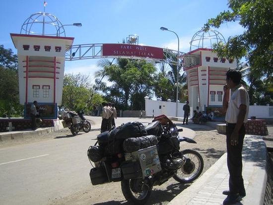 A man standing beside a motorbike at the Indonesia-Timor Leste border