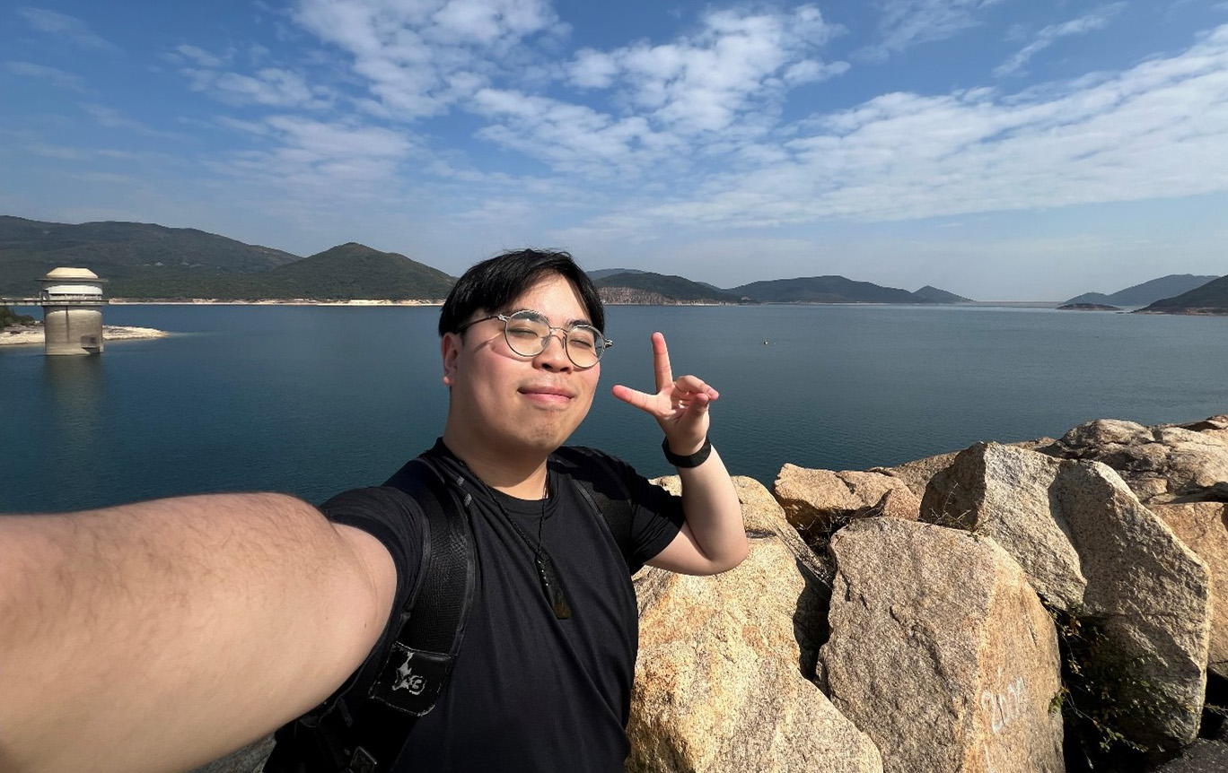 Ruan taking a selfie with a lake and hills behind him