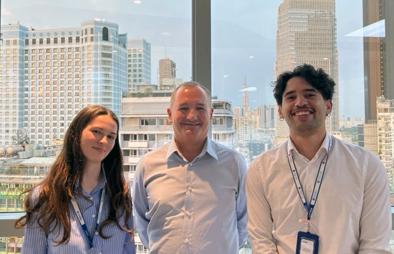 Beth, Warrick Cleine and fellow KPMG intern Karlos Croft posing for a photo in front of a window with tall buildings behind them