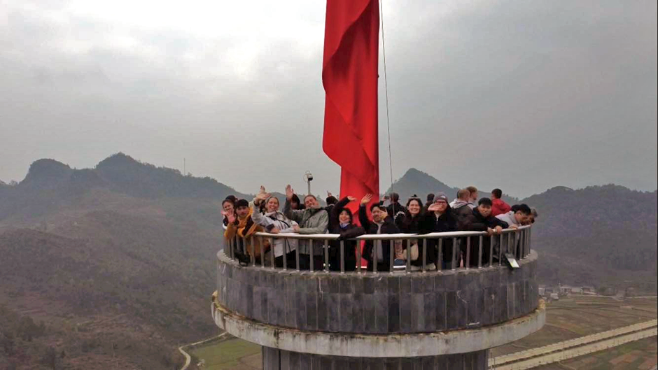 A group of people, including Beth and Karlos, standing on a viewing platform with mountains in the background
