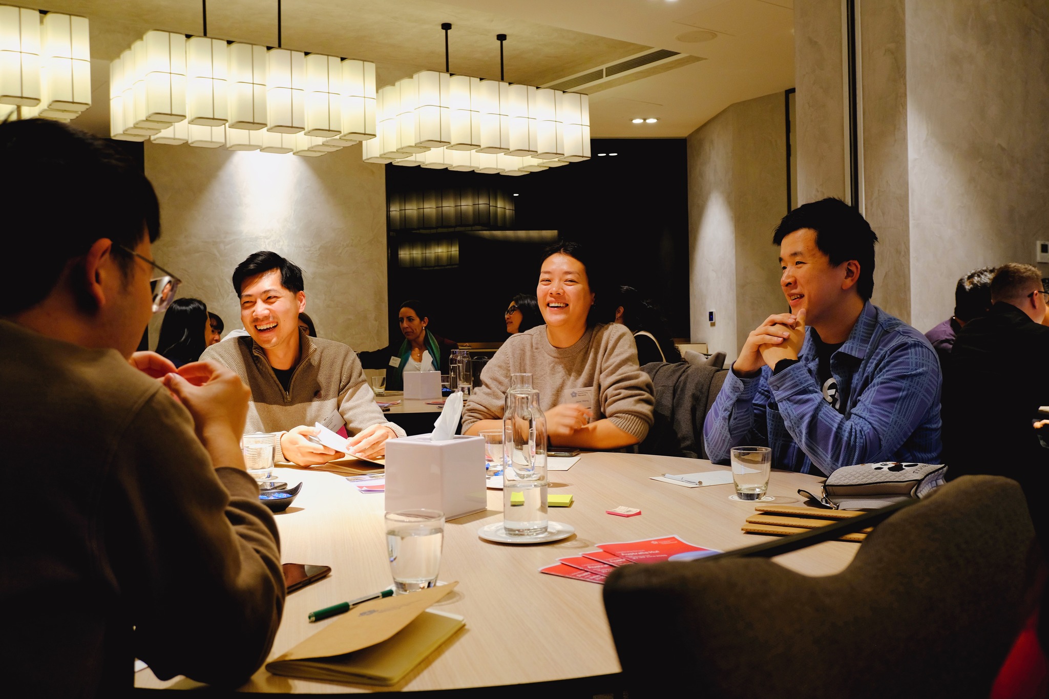 Network members Derek Lieu, Jane Wang and Jimmy Yao sitting round a table during a session on whakawhanaungatanga (relationship building)