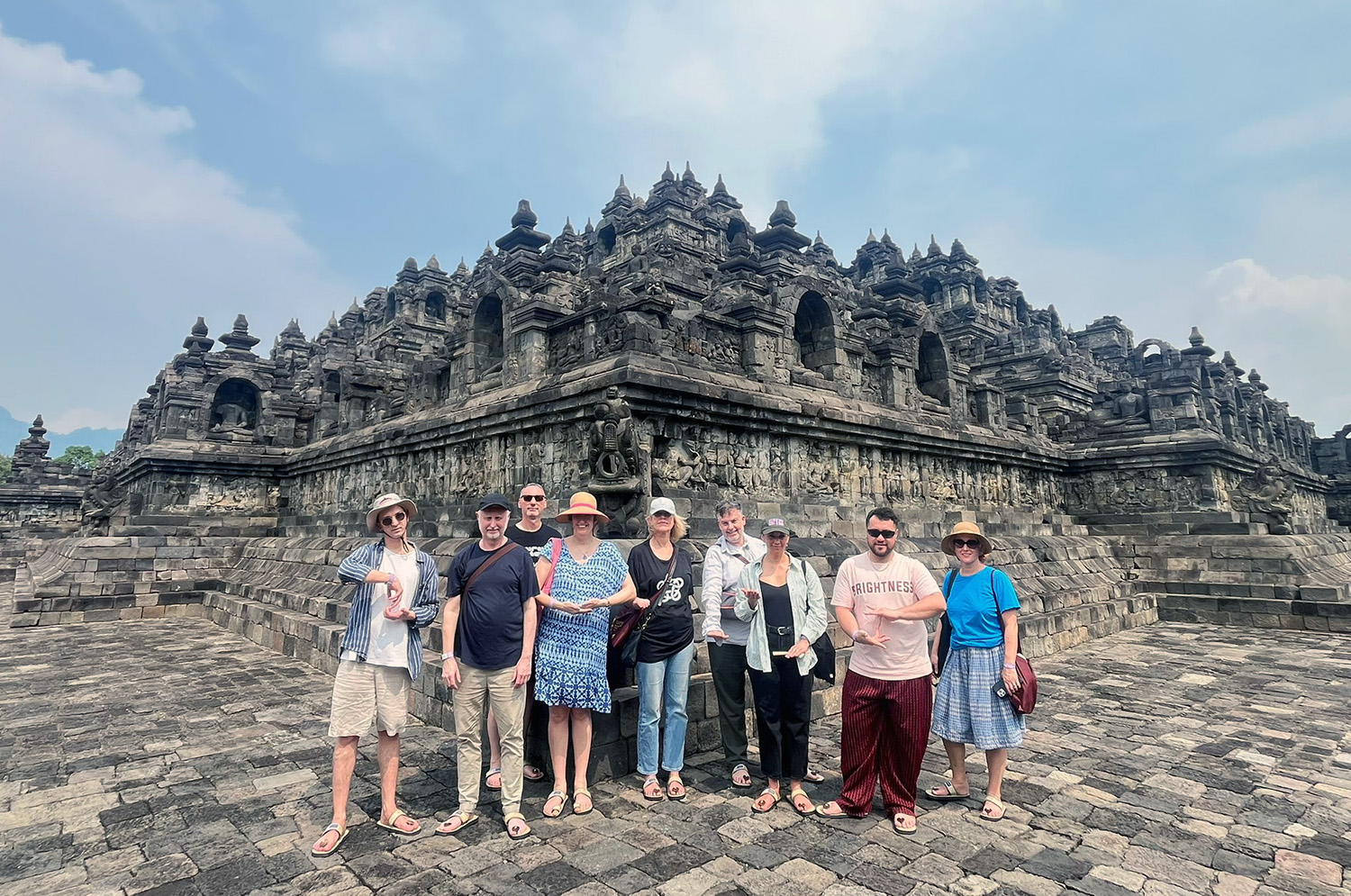 The curators standing for a group photo in front of the carved stones of the famous Borabudur temple near Yogyakarta