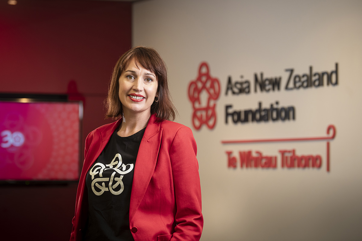 Suzannah Jessep standing in front of an Asia New Zealand Foundation sign