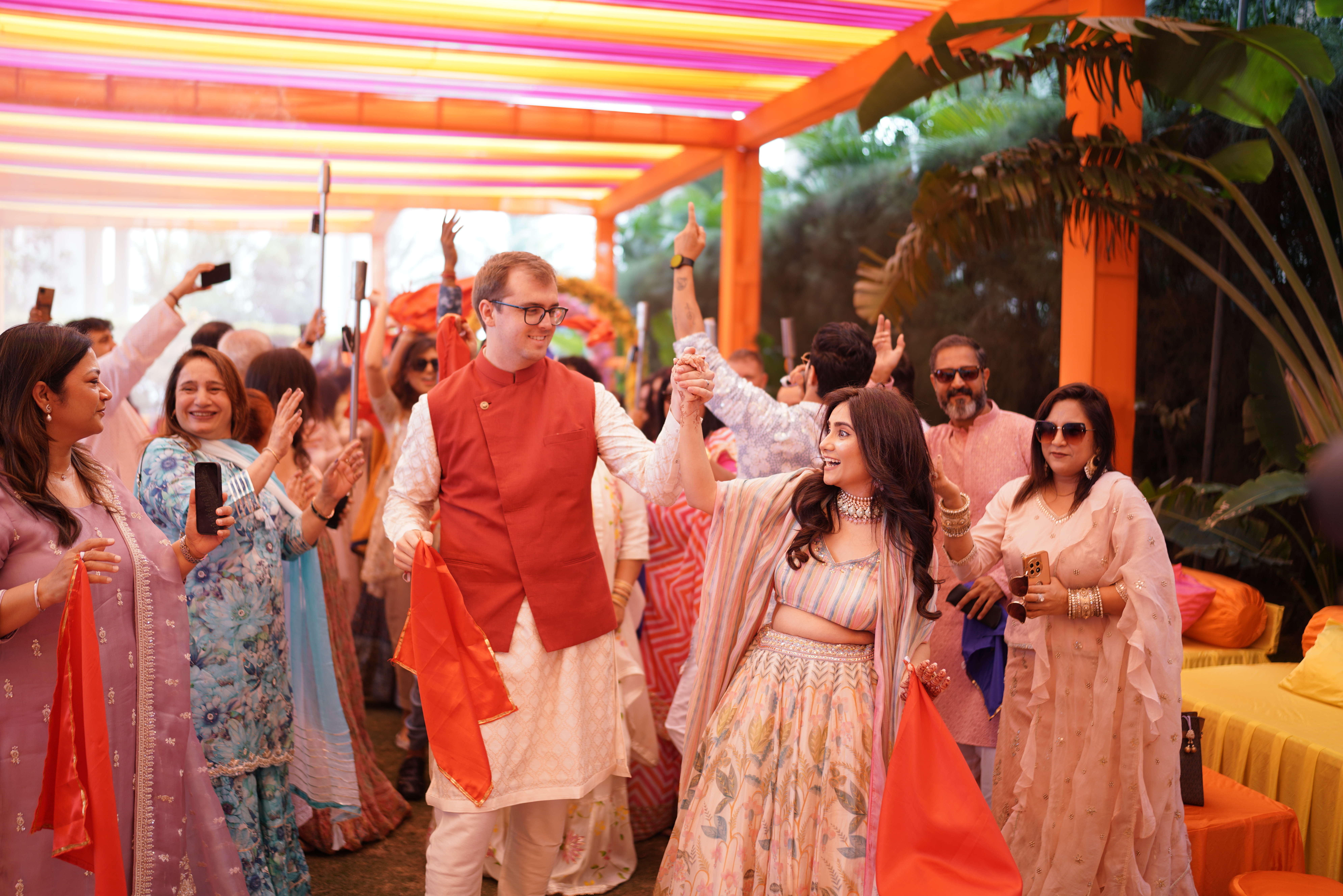 Brent and Anisha dancing through a lineup of people standing under a colourful pergoda