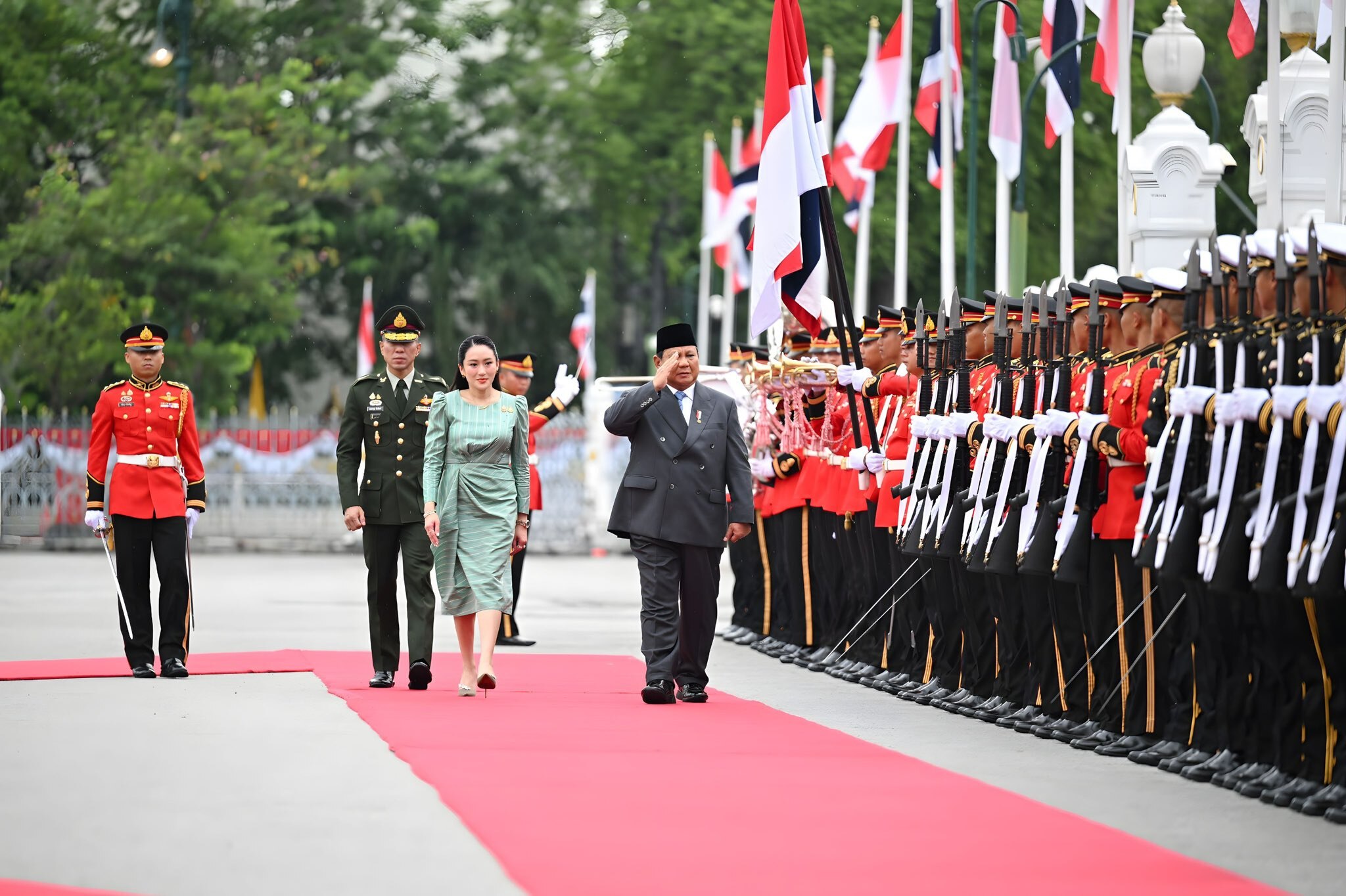 Thai Prime Minister Paetongtarn Shinawatra (left) with Indonesian President Prabowo Subianto Djojohadikusumo walking along a red carpet passing soldiers standing to attention