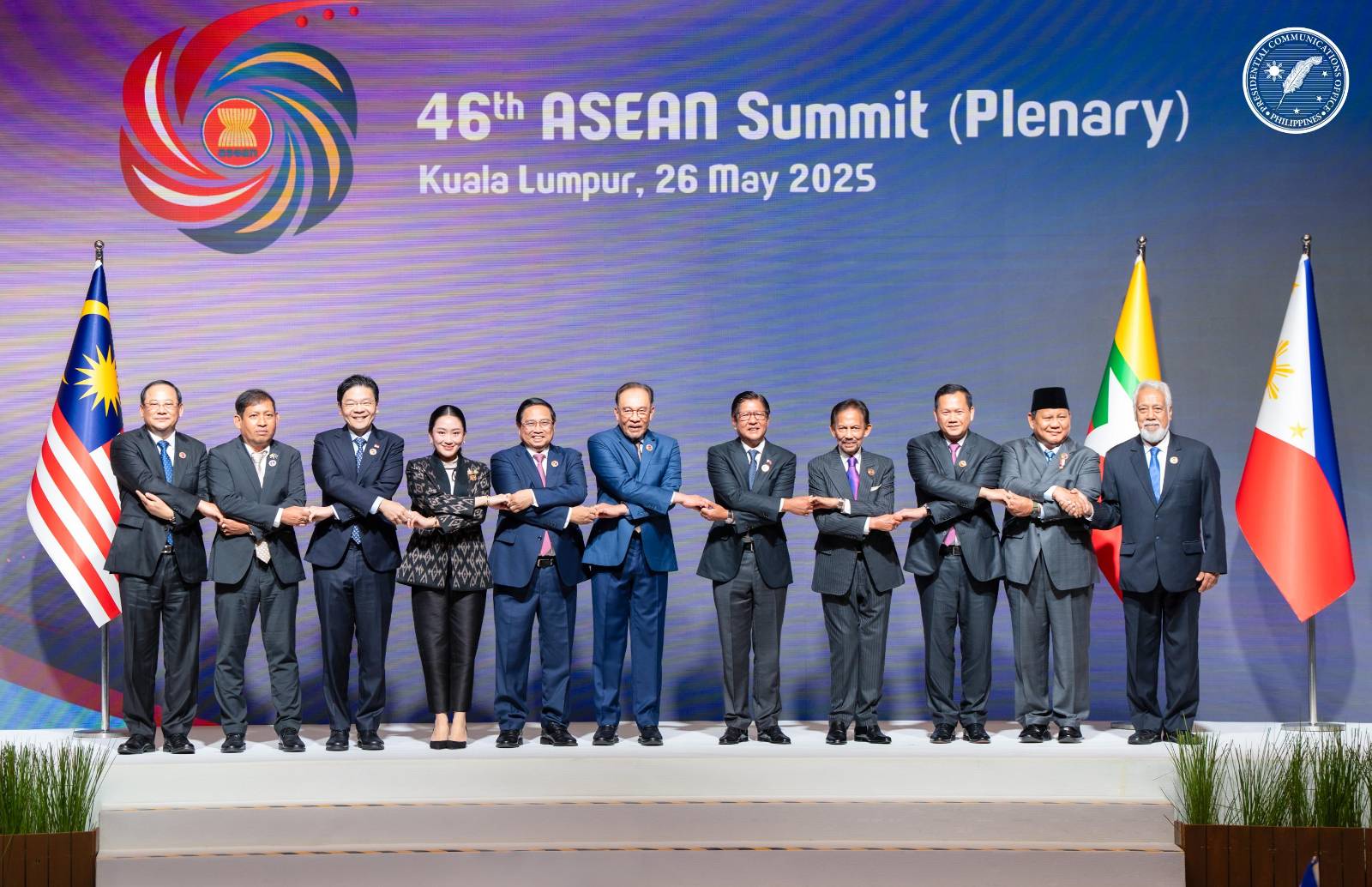 The leaders of the Association of Southeast Asian Nations linking hands and posing for a group photo in front of an ASEAN banner