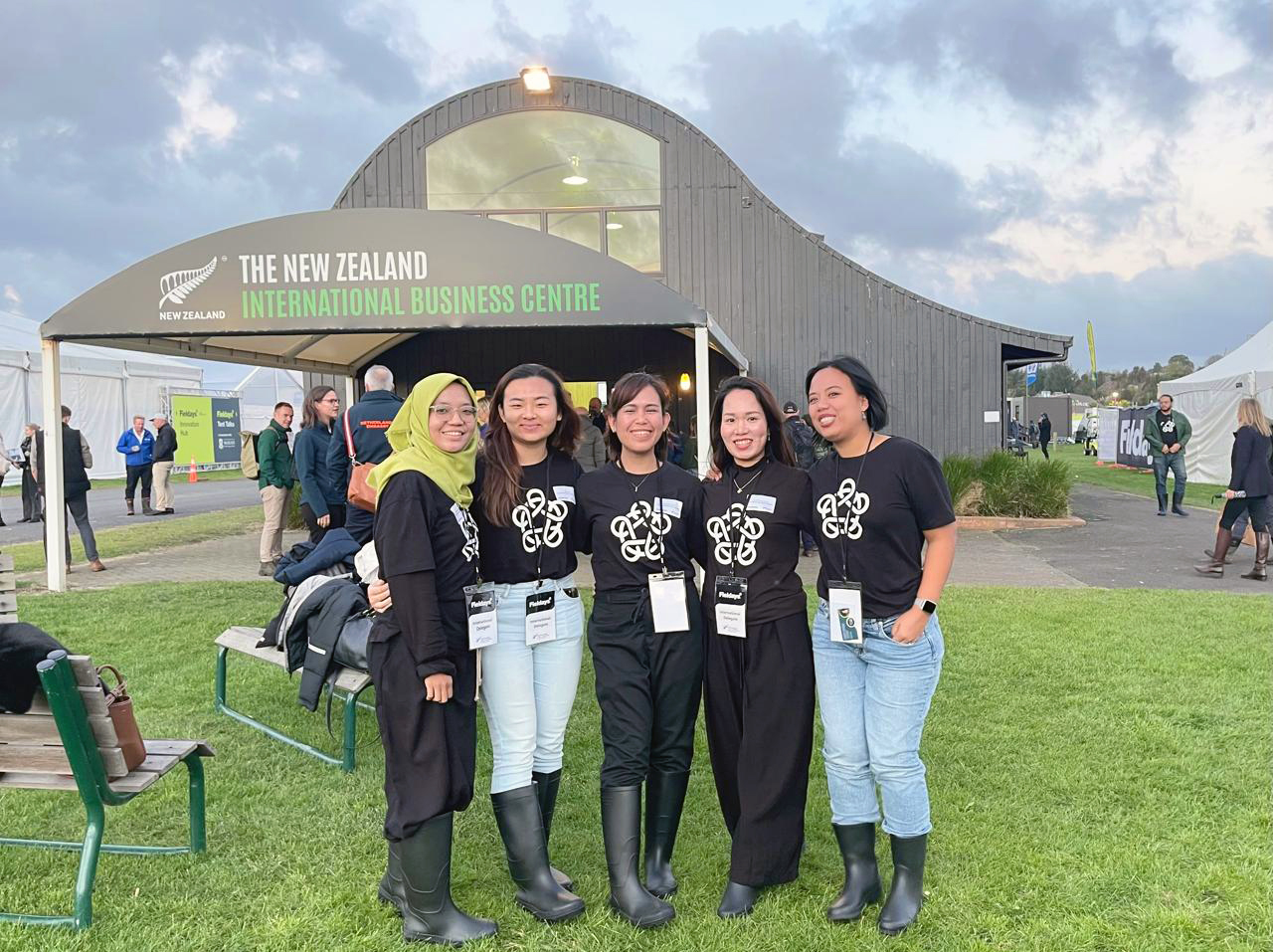 Five of the female entrepreneurs wearing gumboots and Foundation t-shirts standing in front of a barn-like building