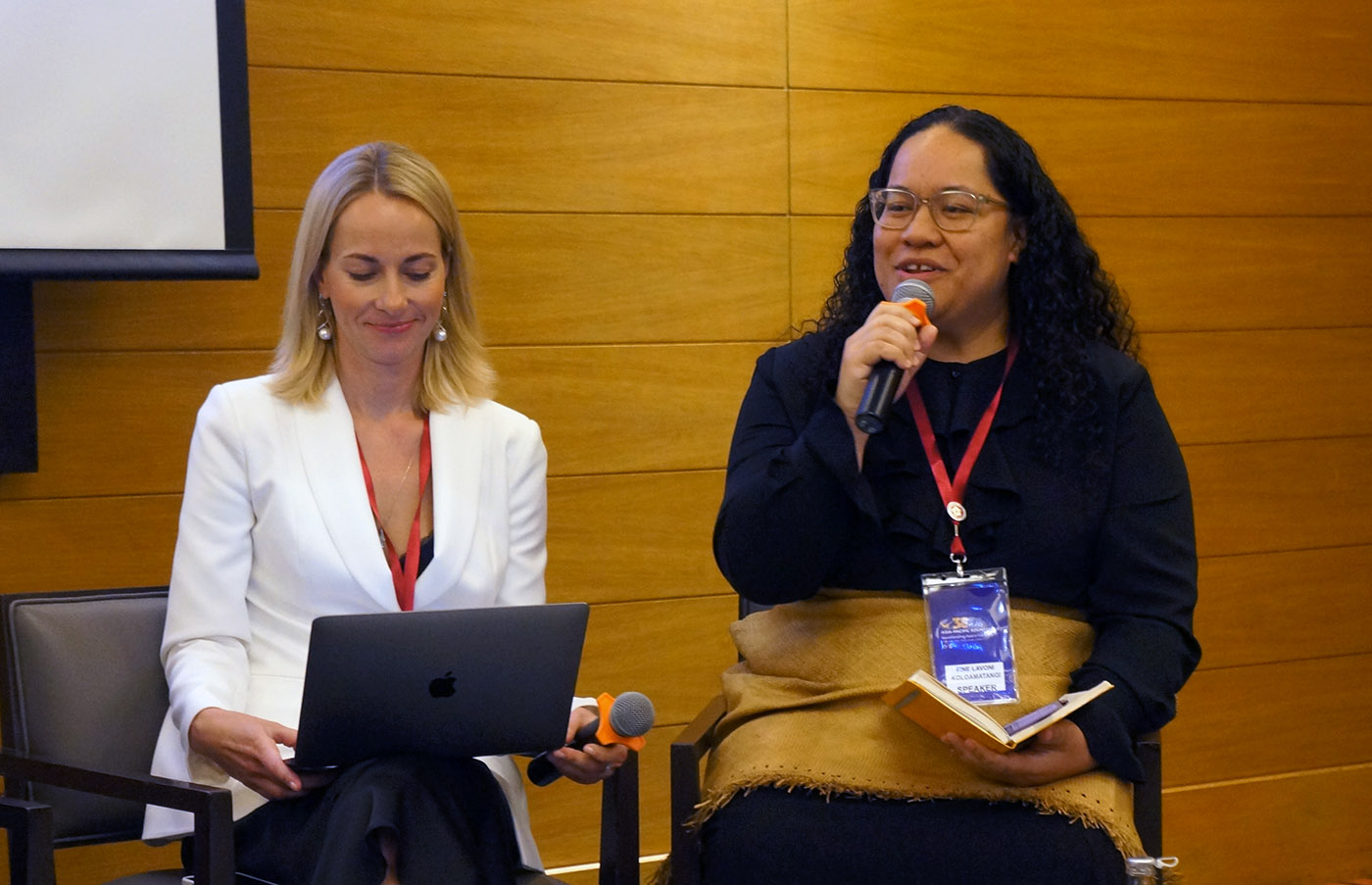 Leadership network member Fine speaking into a microphone with a fellow delegate sitting beside her