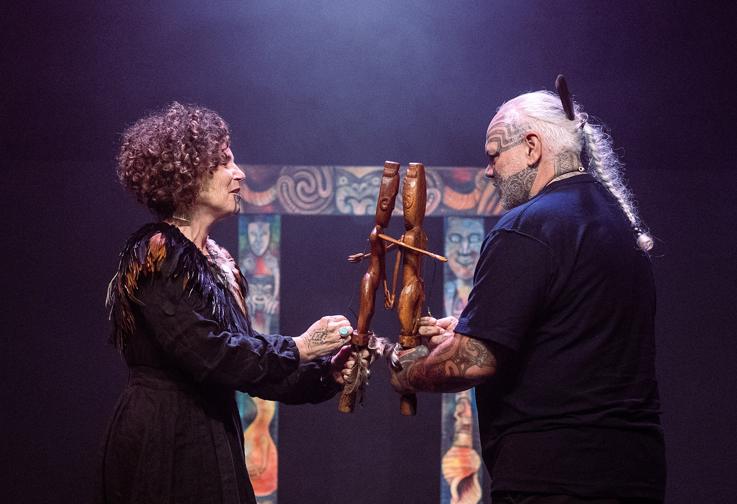 Hinemoa Jones and James Webster on stage holding wooden Maori puppets known as Karetao