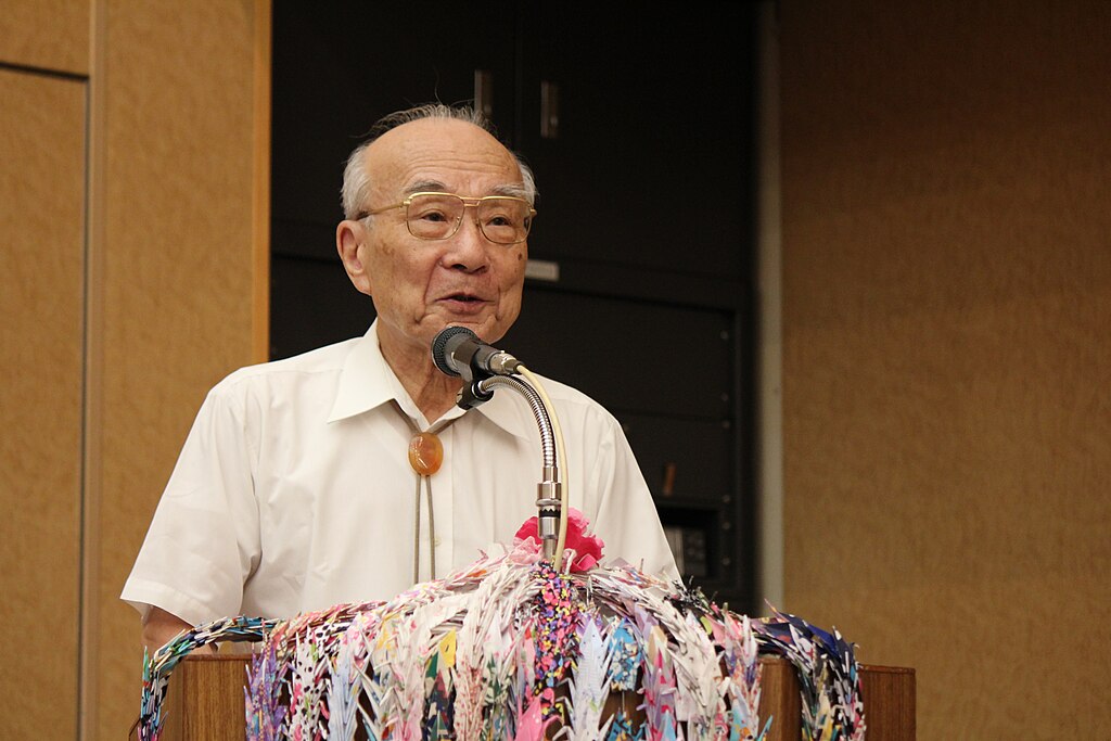 A survivor of the bombing of Nagasaki speaking at a dias