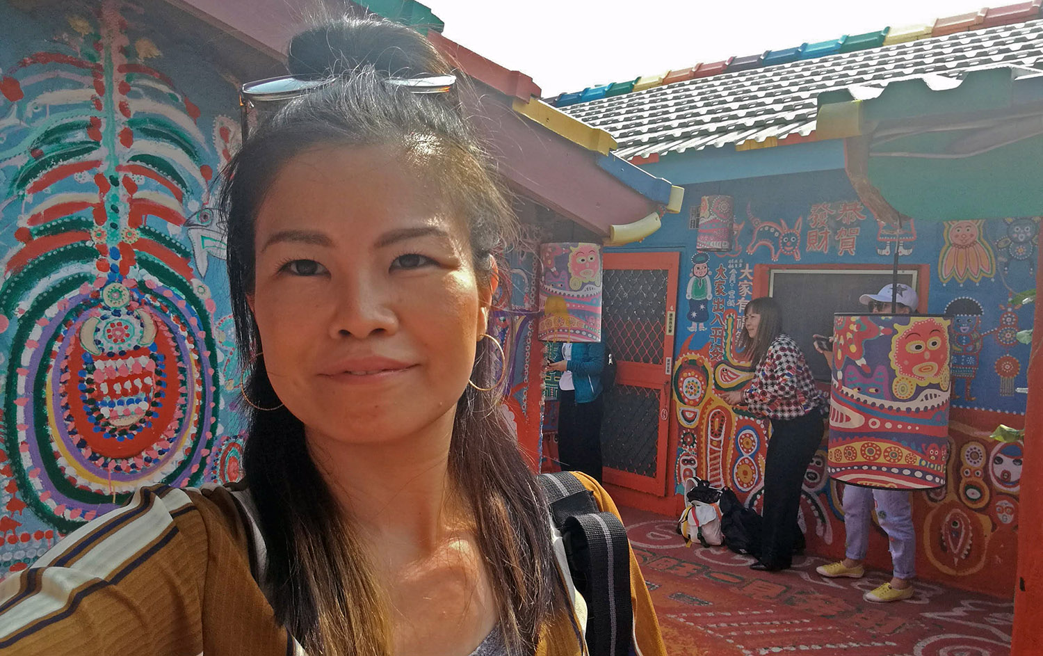 Runa Whitehead taking a selfie in front of a building decorated in brightly coloured abstract images