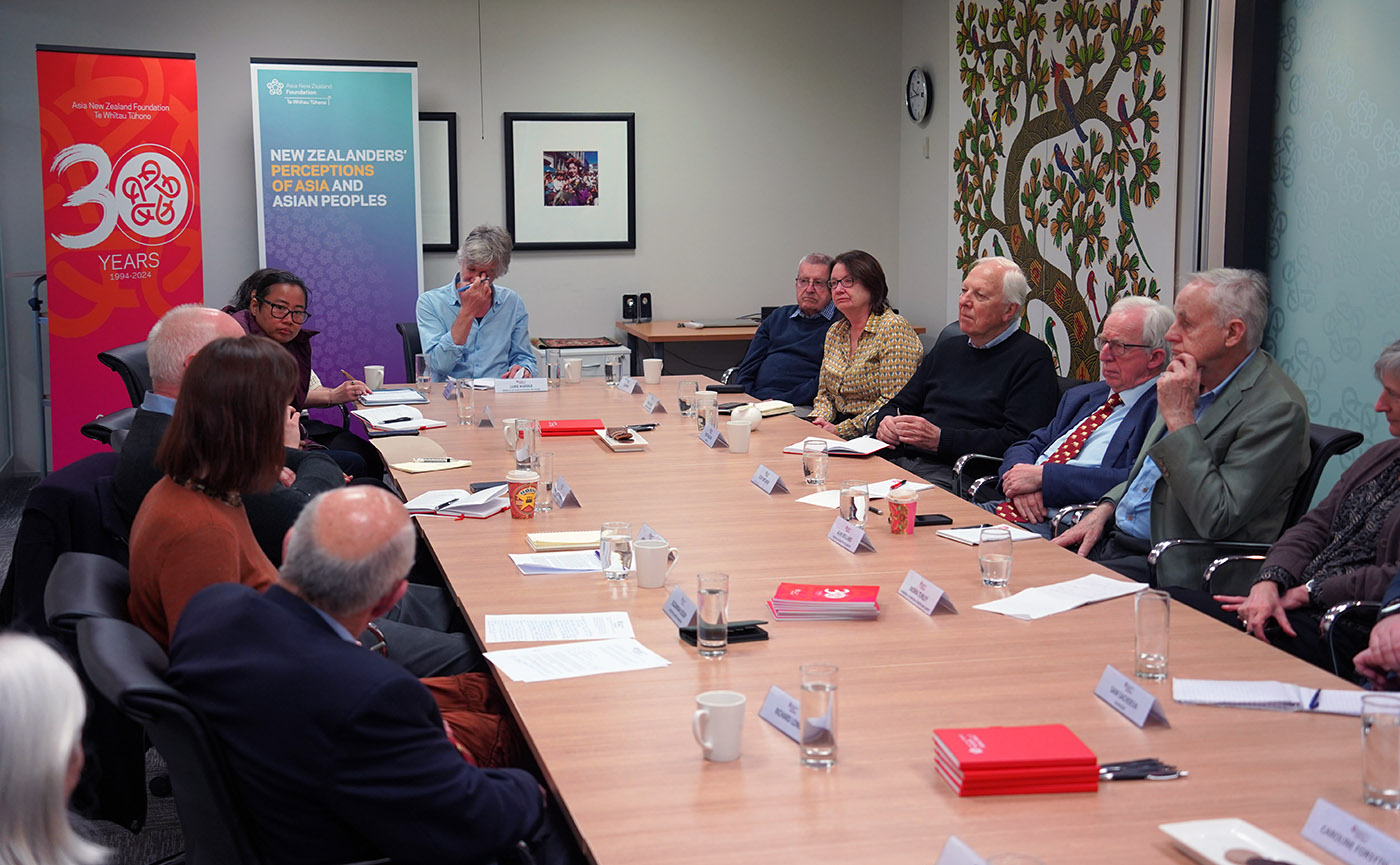 A group of 12 people in discussions around a boardroom table