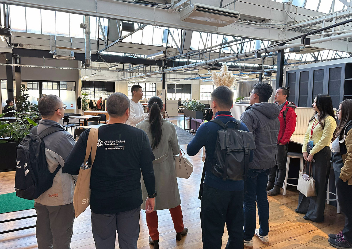 The entrepreneurs listening to a man speak in a large open-plan office