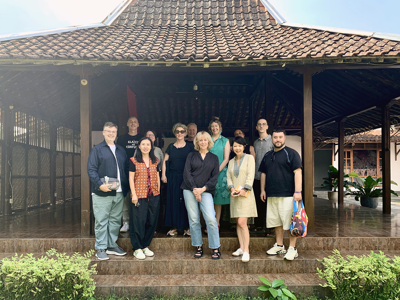 A group of people including Rosana standing in the entrance of a traditional Indonesian building