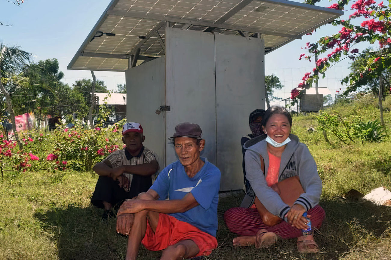 People shelter from the sun under a solar panel