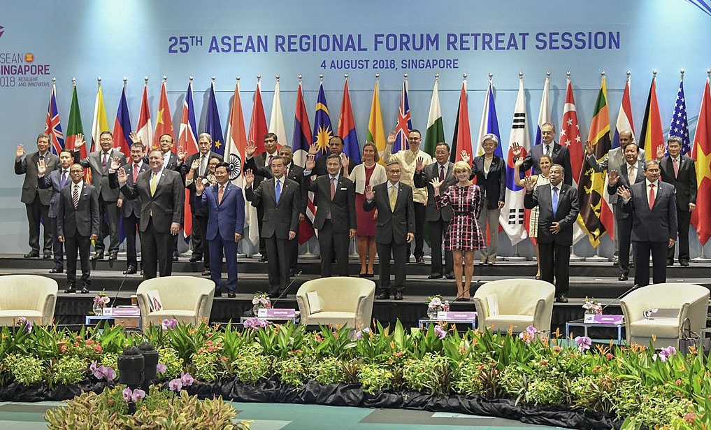 About 30 leaders standing in front of flags a a sign saying 25th ASEAN regional forum retreat session