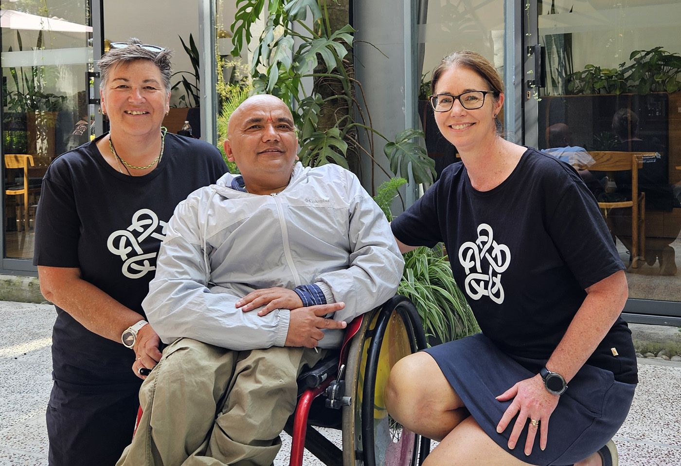 Dr McBean and Dr Harris kneeling beside the deputy secretary general of the Nepal Paralympic Committee, Deepak KC, who is in a wheelchair