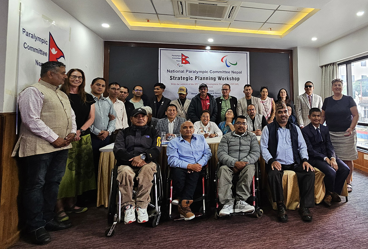 A group shot of 30 people, some in wheelchairs and some standing, posing for a photo in front of a sign reading strategic planning workshop