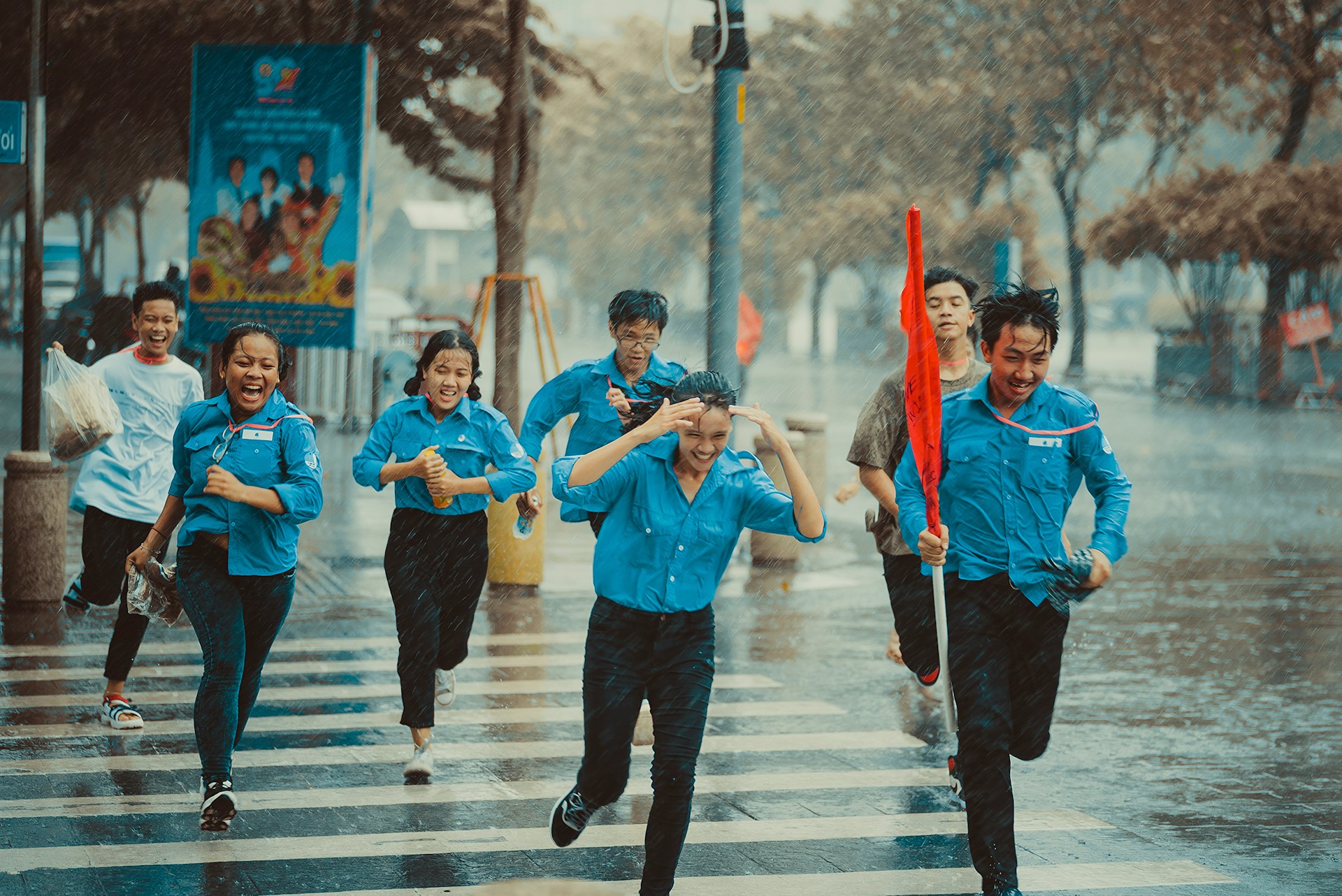 Young people in uniforms running across the road in the rain