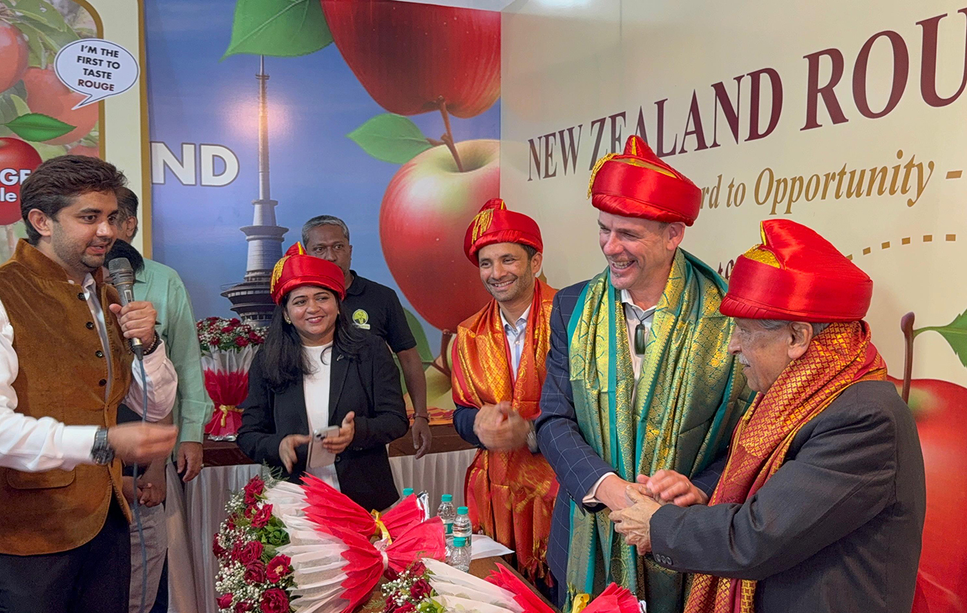 A man speaking into a microphone as two others shake hands