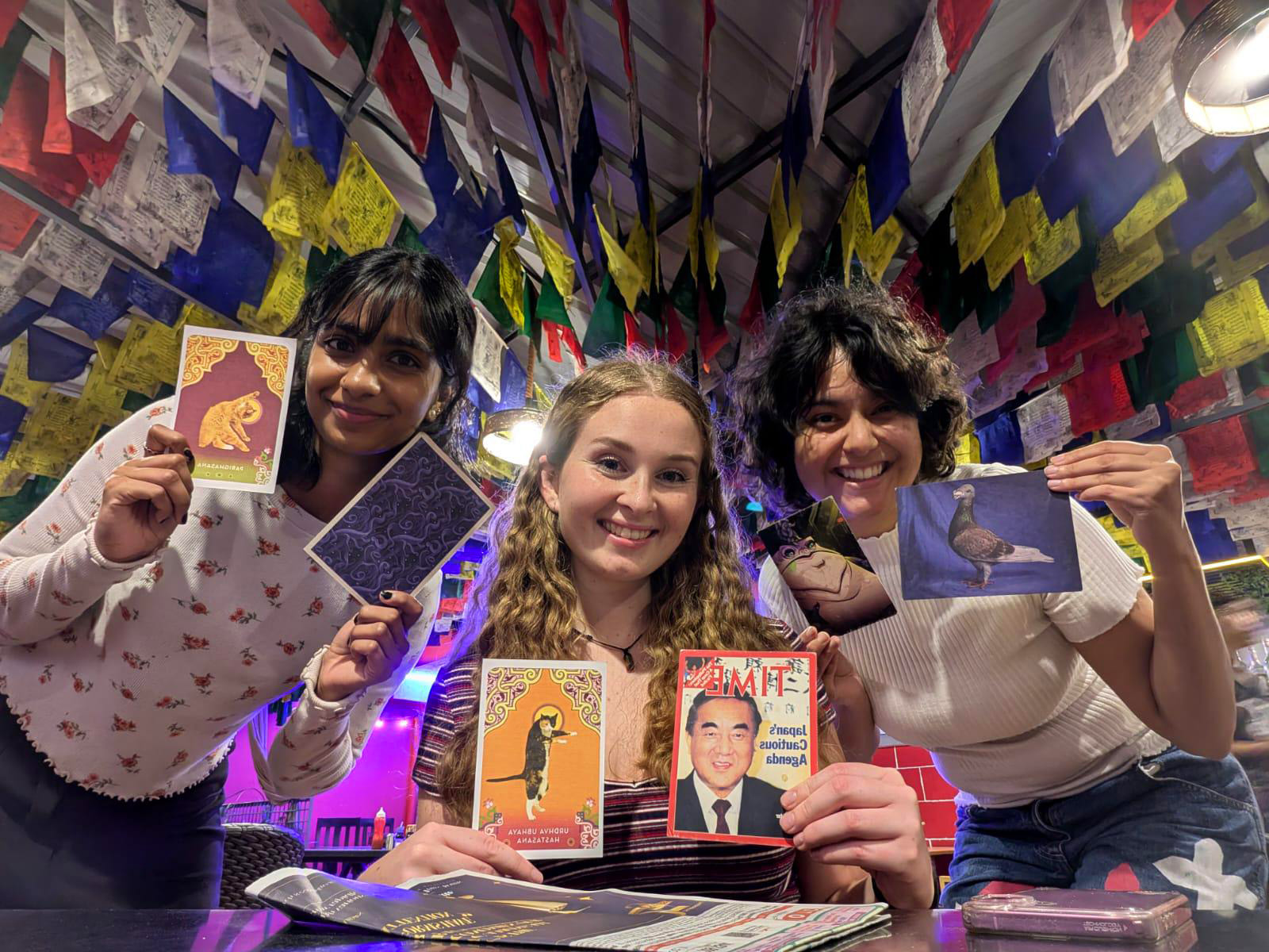 Alison and two young women holding up cards with pictures on them