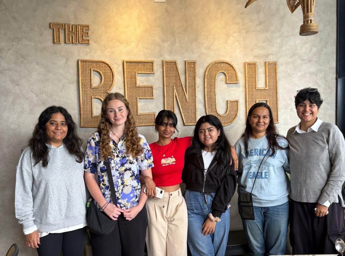 Alison posing in front of a sign reading 'The bench' with five colleagues from UrbanPiper