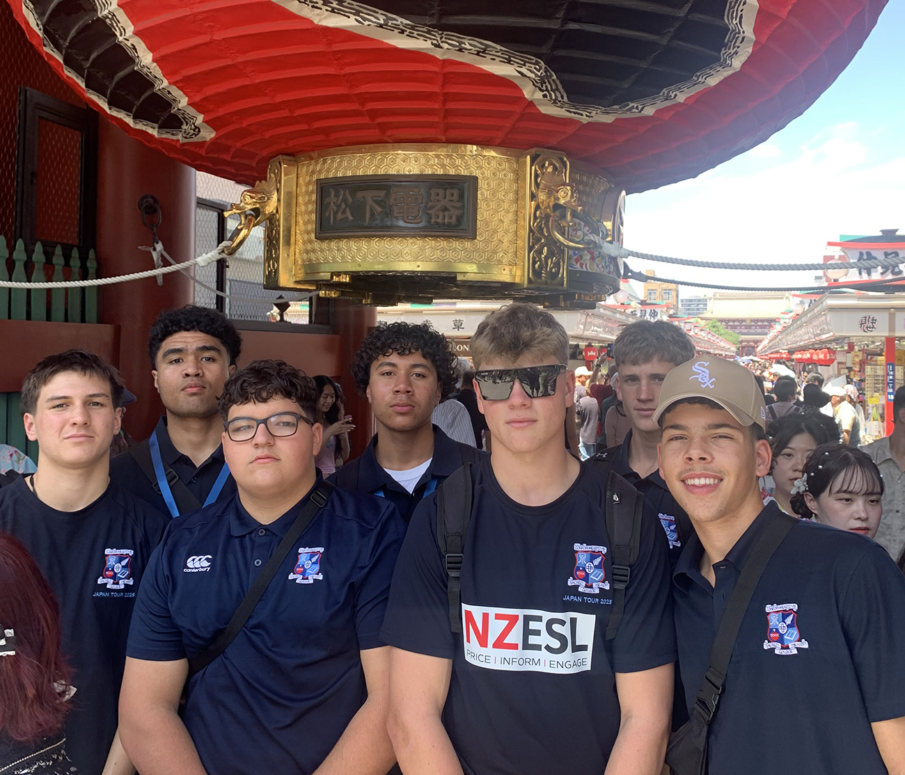 Memebers of the team wearing their team shirts and standing beneath a large red traditional Japaneselantern