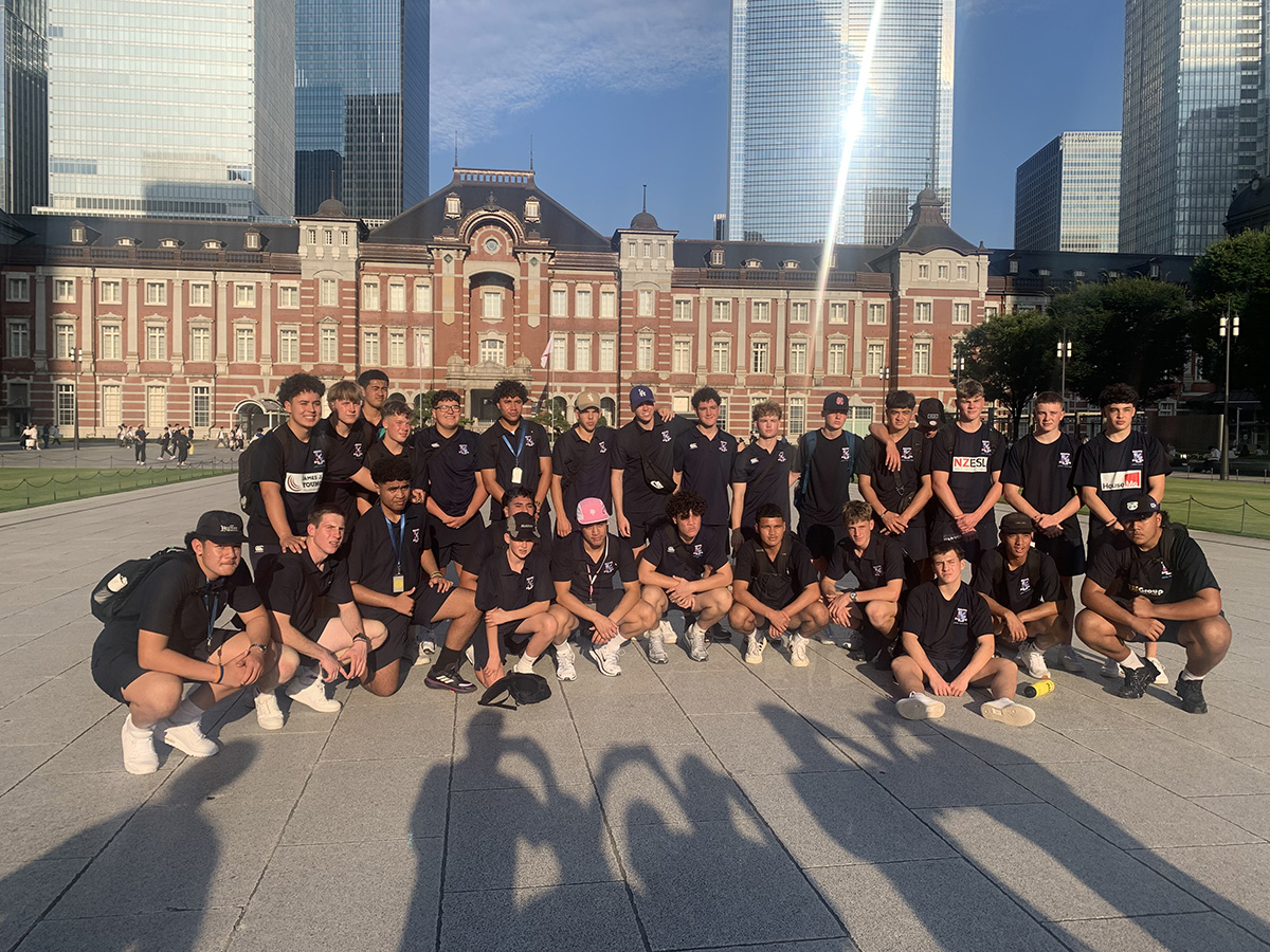 The team posing for a photo in front of a grand old brick building