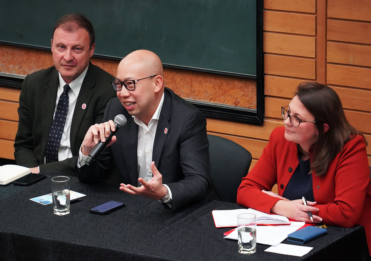 Jason Young, Kenneth Leong and Julia Macdonald sitting on panel.  Kenneth holds the microphone and is speaking to the auidence