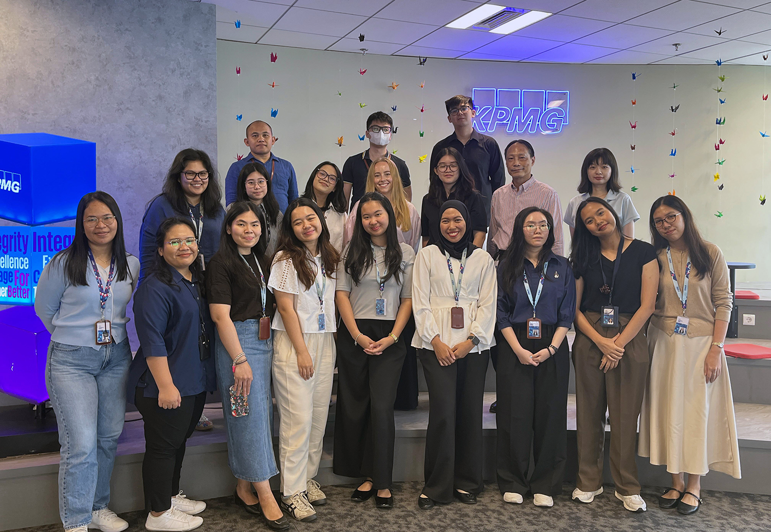 Olivia posing for a group photo with a group of about 15 collagues from KPMG