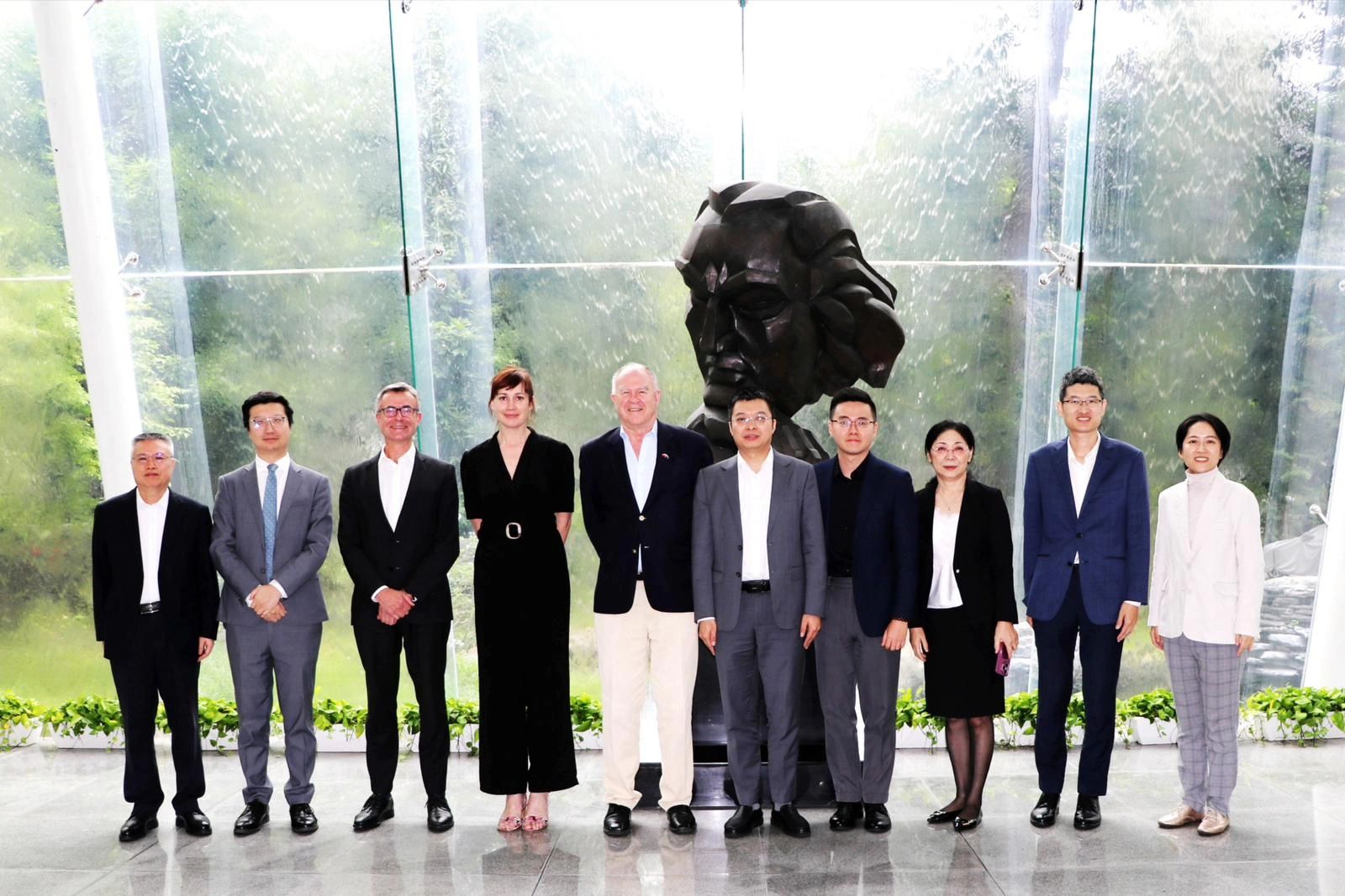 The New Zealand delegation alongside China Development Institute delegates and New Zealand Consul Michael Zhang standing in a foyer with large glass windows looking out onto greenery