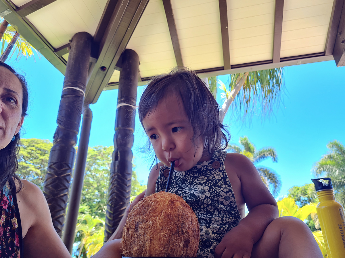 Dionte with her baby daughter who is drinking with a straw from a coconut