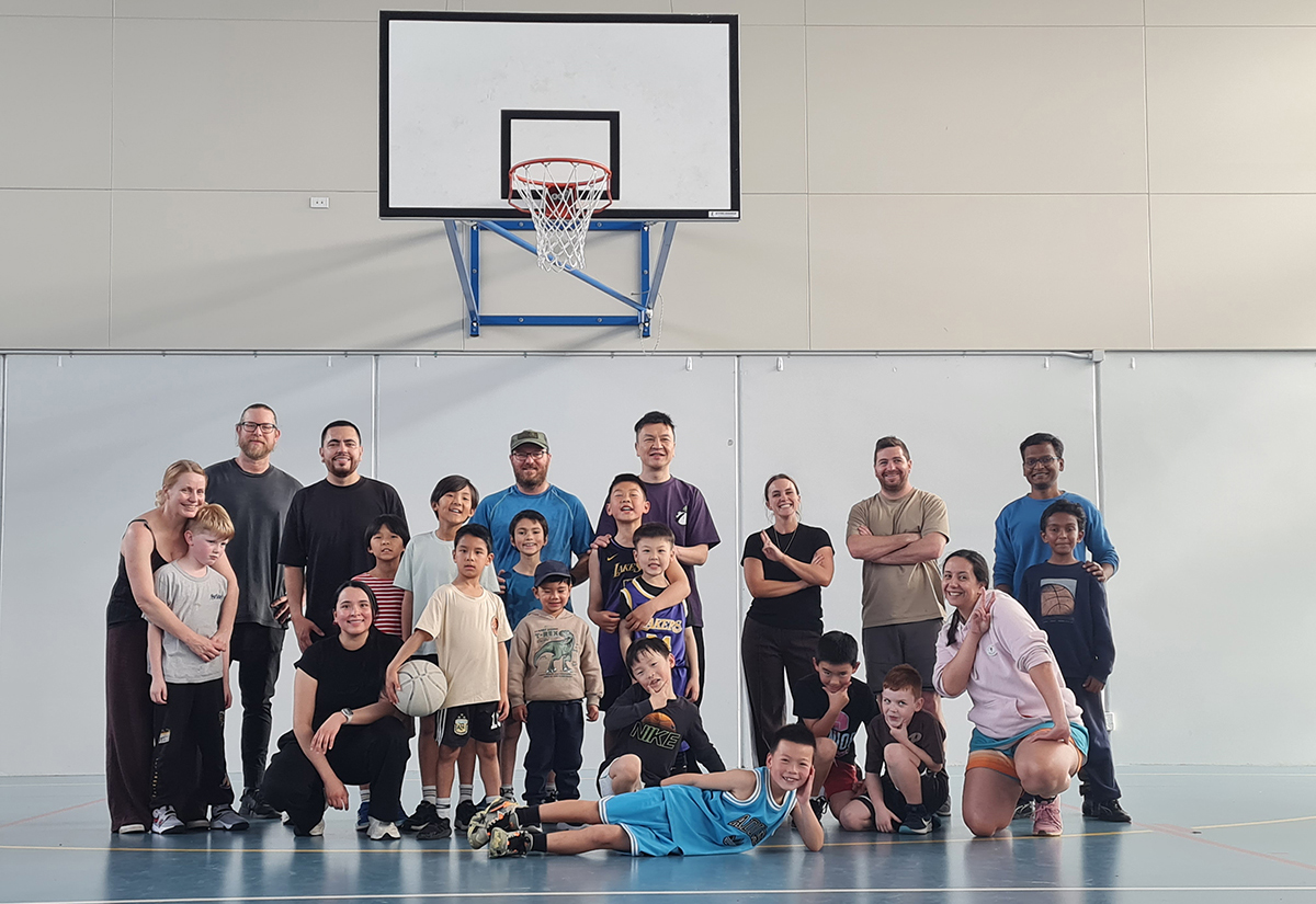 Dionte with a group of 15 people standing beneath the hopp of a basketball hoop
