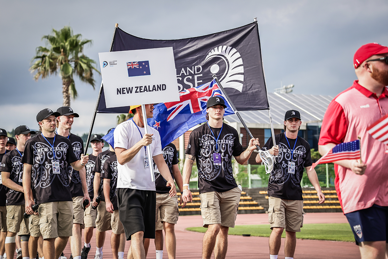 The New Zealand team being led into a lacrosse ground behind their flag bearer