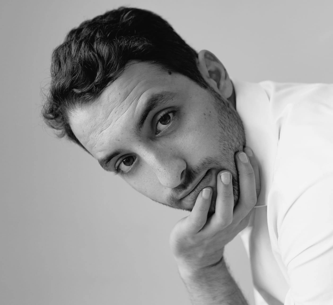 Black and white image of a man with a hand to his chin