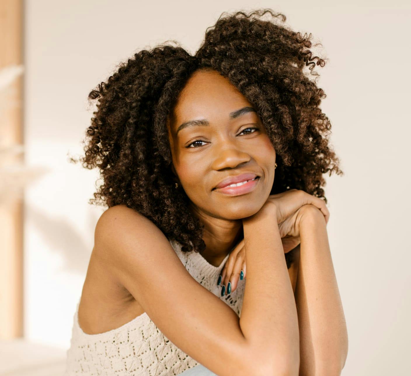 Woman with curly hair holding her hands to her head
