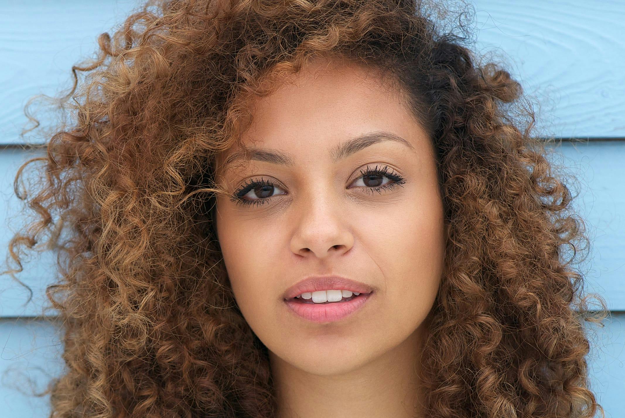close up of woman in front of blue wood siding