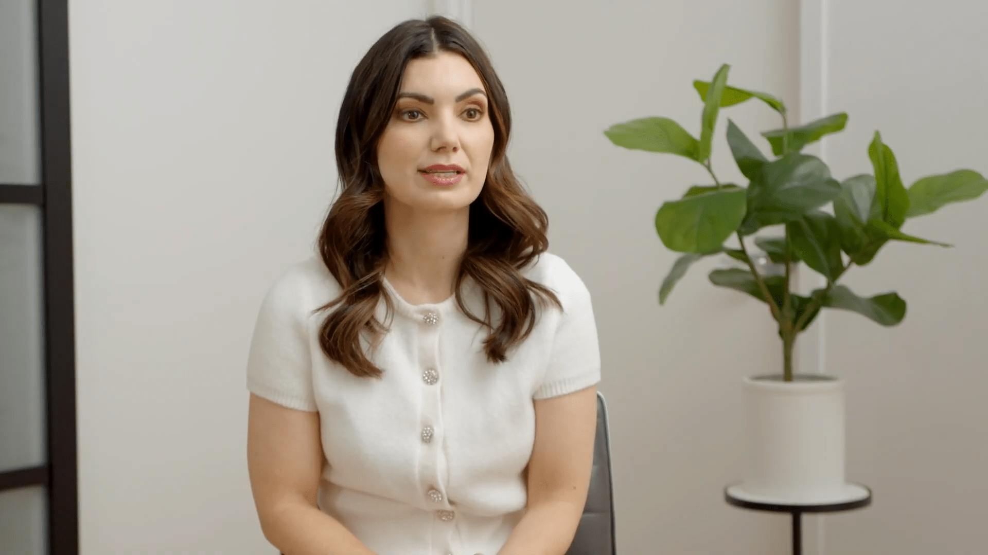 Dr Anais in white, sitting on a chair