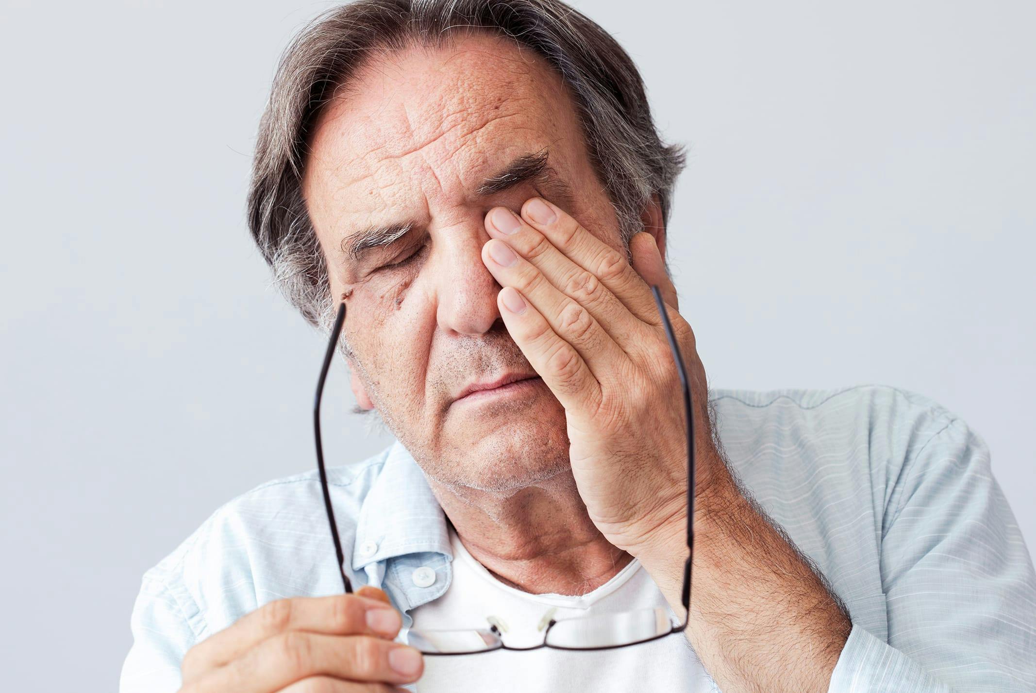 man touching eye in pain