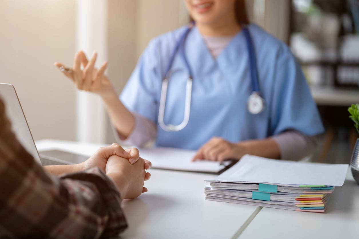 Doctor sitting at desk with patient with patient files